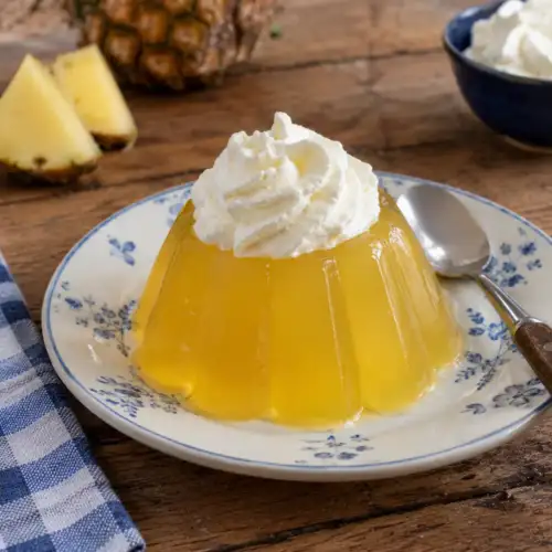 Frisse ananasgelei van ananassap en gelatine geserveerd met een toef slagroom