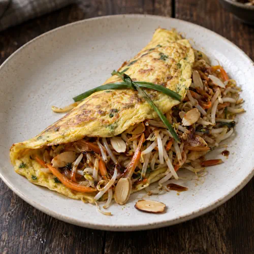 Indonesische taugéomelet met winterwortel, bieslook, amandelen en ketjap manis.