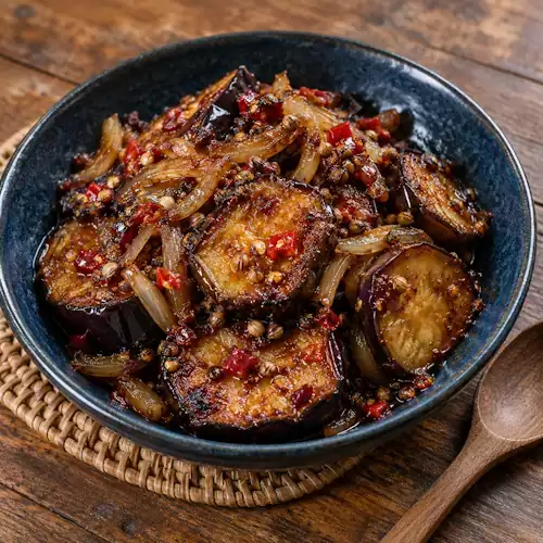 Gebakken aubergine met tamarindesaus, ui, lombok en ketoembar.