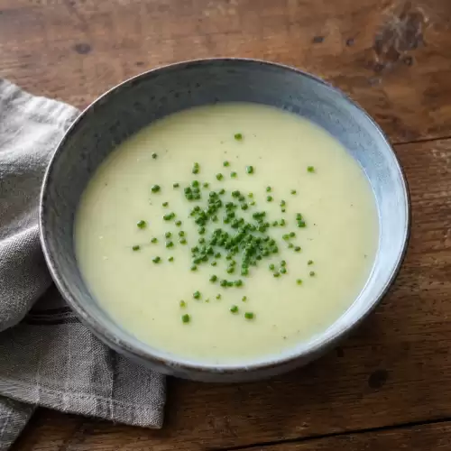 Romige vichyssoise van aardappel en prei, afgewerkt met bieslook.